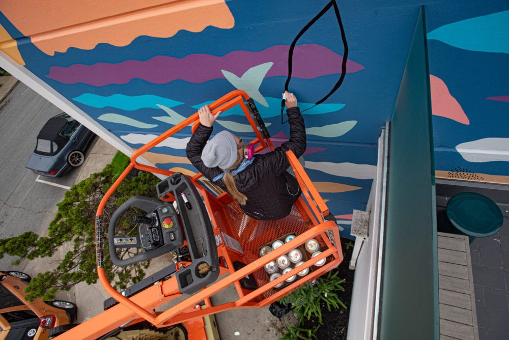 Aerial view of Priscilla on orange crane painting mural