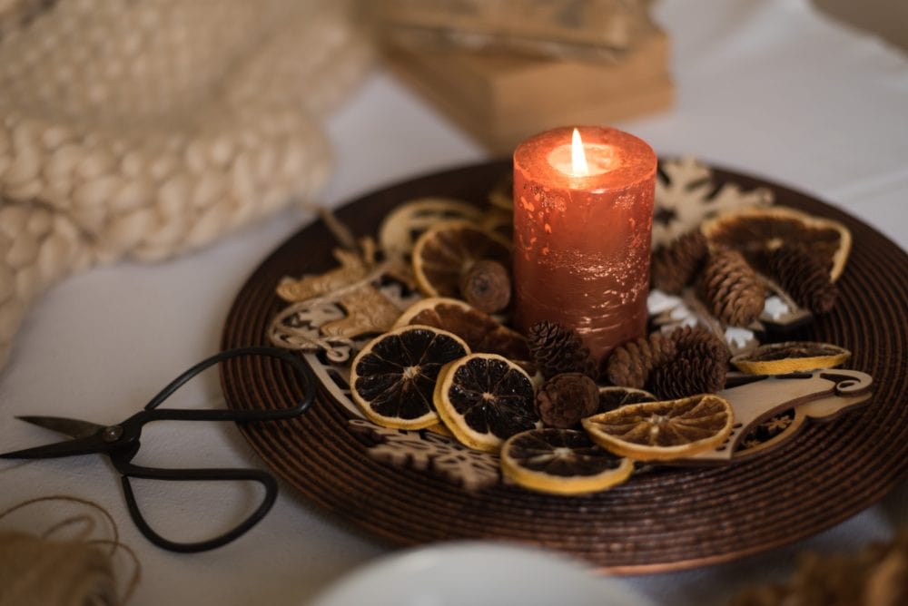 orange candle on tray with dried citrus slices surrounding it.