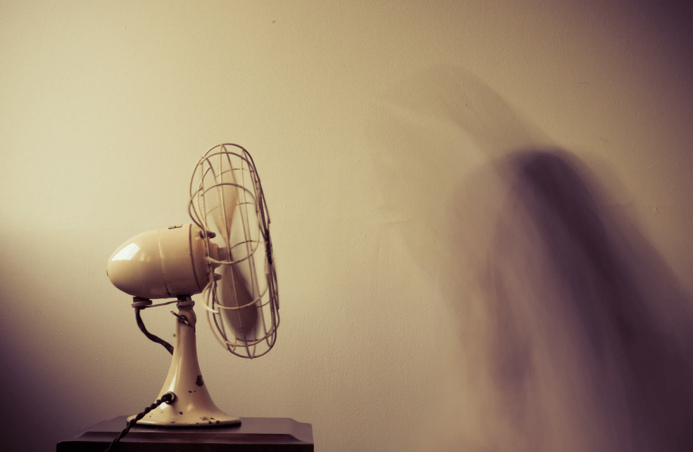Retro fan on table against tan wall, side view
